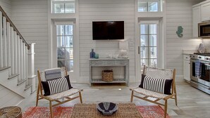 A spacious living room with two wicker chairs, a coffee table, and a flat-screen TV mounted on the wall. - Seahorse Cottage 230 RO C1 (Port Aransas)