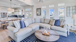 A spacious living area with a large L-shaped sectional sofa, a round coffee table, and a ceiling fan.