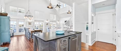 Una cocina amplia con una isla grande, piso de madera e iluminación colgante.