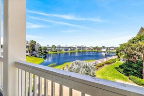 A residential area with a large body of water, likely a pond or lake, surrounded by houses with manicured lawns and palm trees. - Sea Ya' 204 GU (Port Aransas)