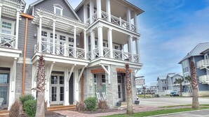 A multi-story residential building with a balcony, stone facade, and a well-maintained lawn. - Sandy Feet Retreat TC 9106 (Port Aransas)