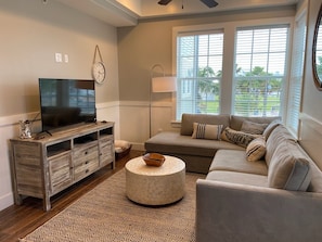 Relax in this stylish living room with a large flat-screen TV, comfortable sofa, and cozy ottoman.