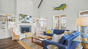 A spacious living room with a fireplace, a blue sofa, and a decorative fish on the wall. - Summer Catch 401 COA (Port Aransas)