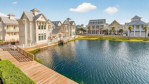 A waterfront property with multiple houses connected by a wooden deck. - Sun Chaser Cottage 205 Fiv-d (Port Aransas)