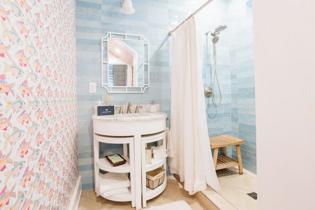 A bathroom with a white vanity, a shower with a handheld showerhead, and a patterned wall.