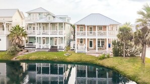 A waterfront property with multiple buildings, including a large house with a balcony and a smaller house with a porch. - The Veranda 141 BE (Port Aransas)