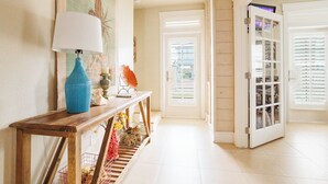 A hallway with a wooden console table, a blue vase, and a painting on the wall. - The Veranda 141 BE (Port Aransas)