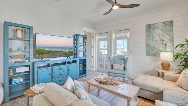 A living room with a TV, blue cabinets, a sofa, and a ceiling fan. - Seaside Cabana TC 10302 (Port Aransas)