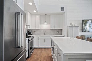 A modern kitchen with white cabinetry, stainless steel appliances, and a large island.