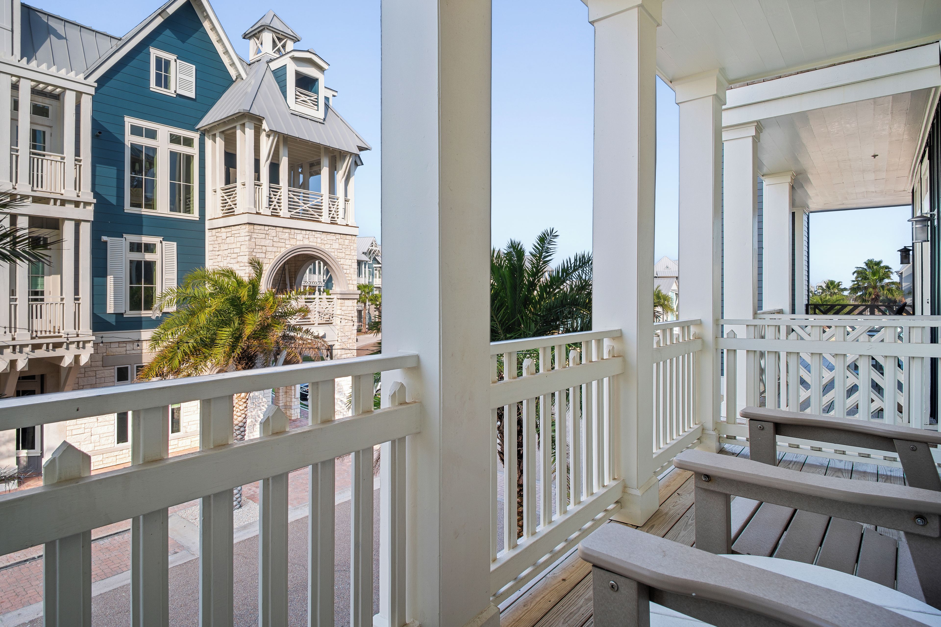 A balcony with white railings overlooking a street with buildings.