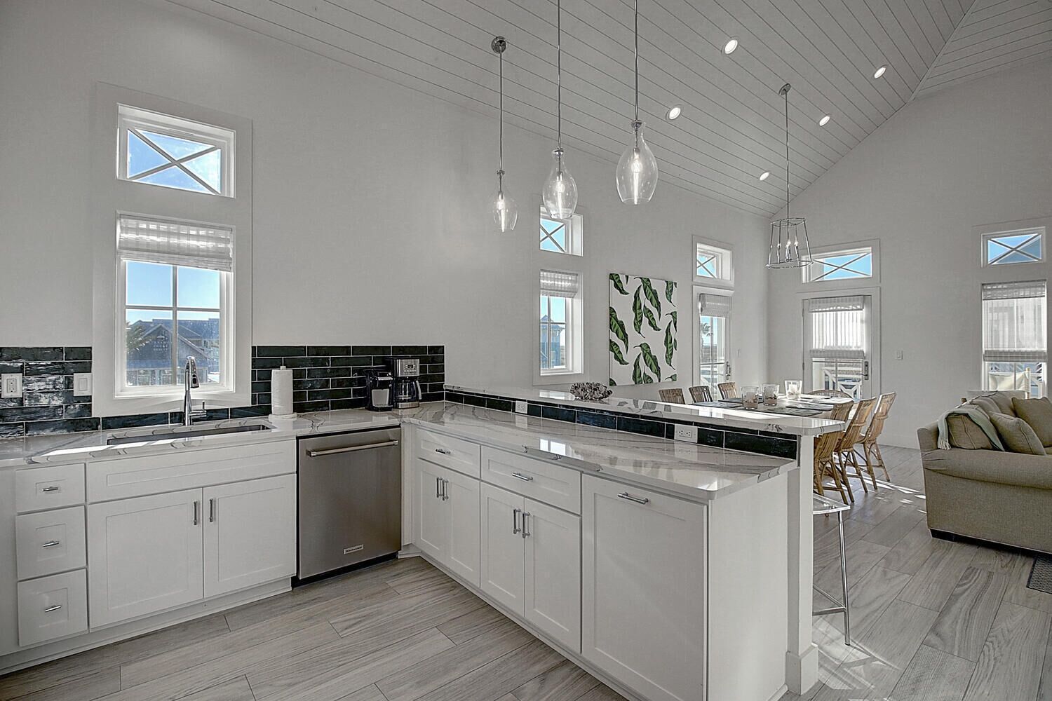 Una cucina moderna con mobili bianchi, un'isola grande e illuminazione a sospensione.