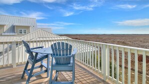 A deck with a table and two chairs, overlooking a barren landscape. - Sippin' on Sunshine 164 BE (Port Aransas)