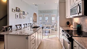 A spacious kitchen with a central island, stainless steel appliances, and a view to the dining area. - Latitude Adjustment TC 3305 (Port Aransas)