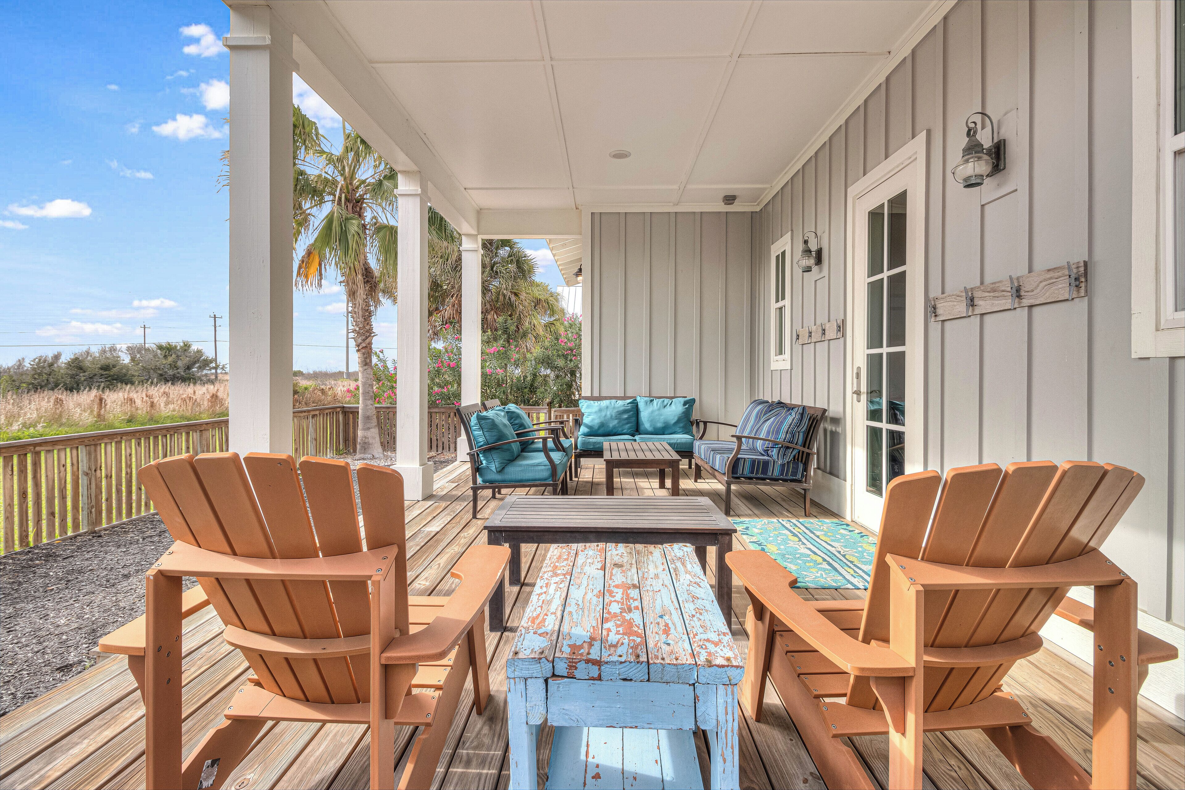 A covered deck with wooden chairs, a table, and a sofa.