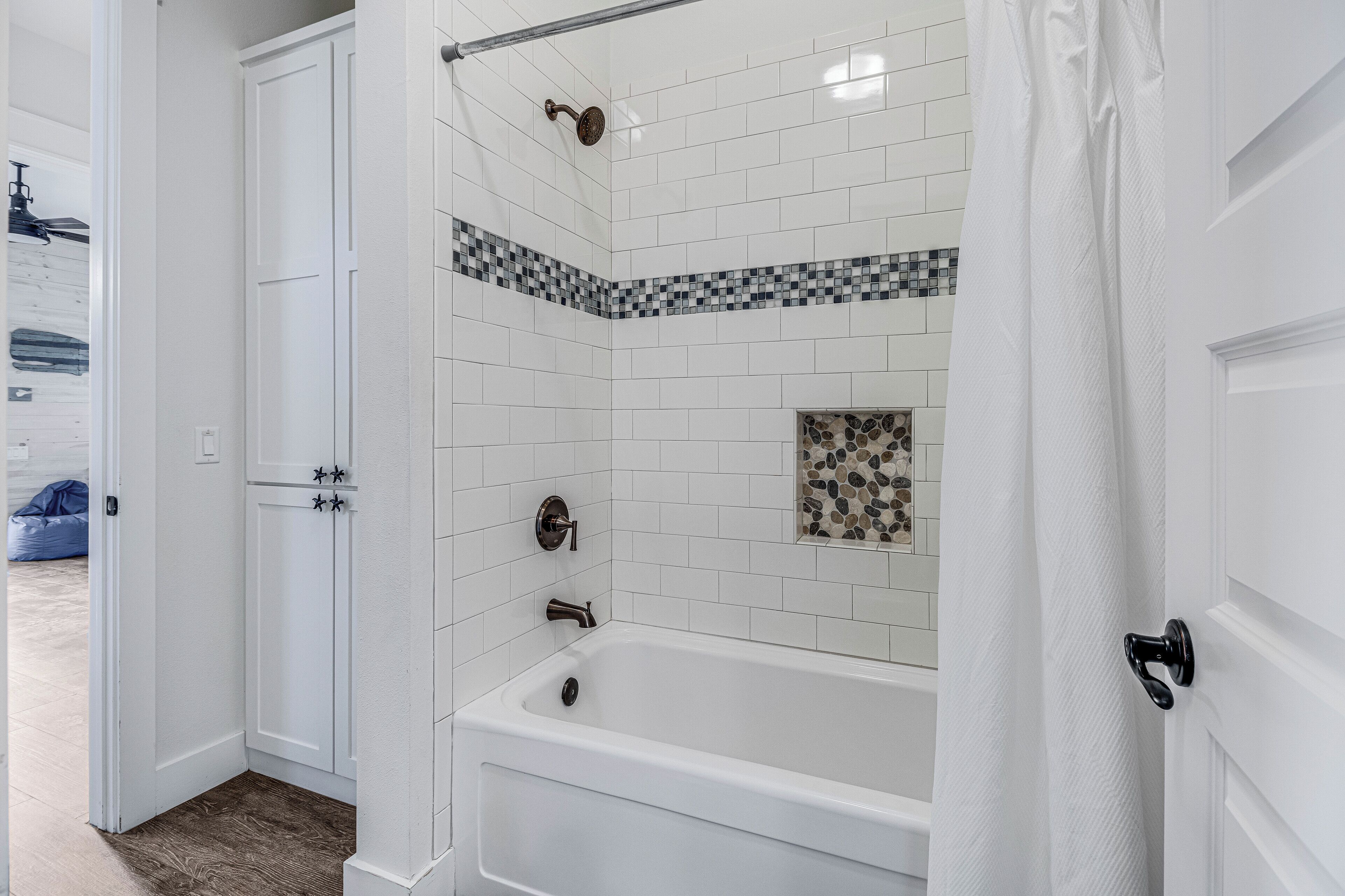 Un bagno con una vasca da bagno bianca, una doccia con soffione a pioggia e uno spazio doccia piastrellato.