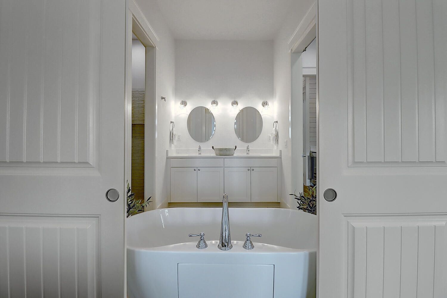 A bathroom with a white sink, two round mirrors, and a vanity with a mirror above it.