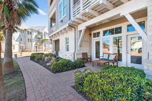 A modern building with a brick pathway, outdoor seating, and well-maintained landscaping. - Saltwater Cove TC 2103 (Port Aransas)