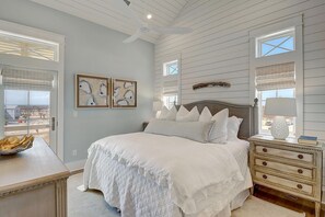 A bedroom with a large bed, a dresser, and a window with blinds. - The Lighthouse 328 COA (Port Aransas)