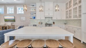 A spacious kitchen with a large island, white cabinetry, and pendant lighting.