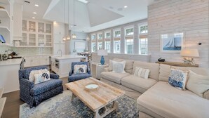 A spacious living area with a high ceiling, white cabinetry, and a large window providing natural light.