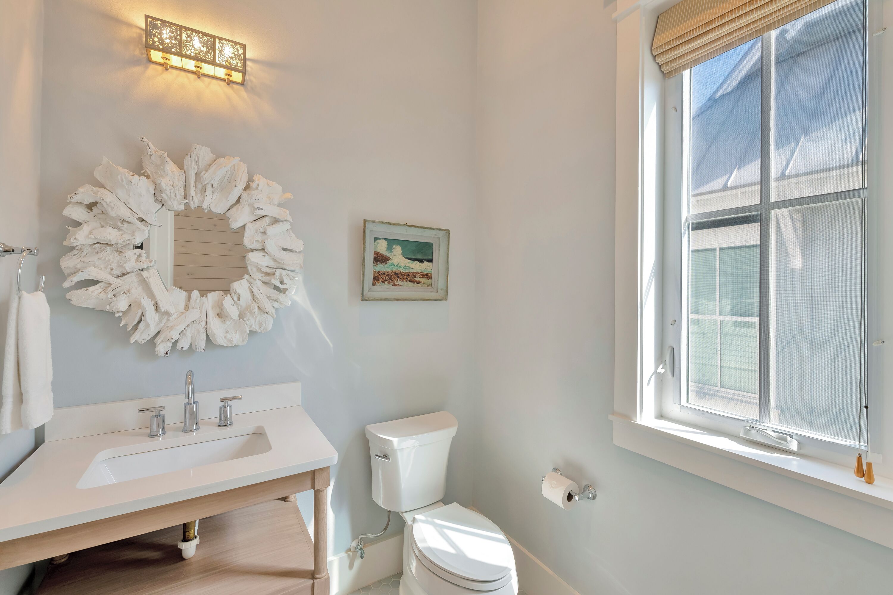 A bathroom with a white sink, toilet, and a large window.