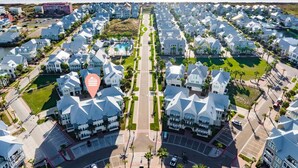 A coastal residential area with white houses, a central road, and a beach in the background. - The Hideout TC 10101 (Port Aransas)