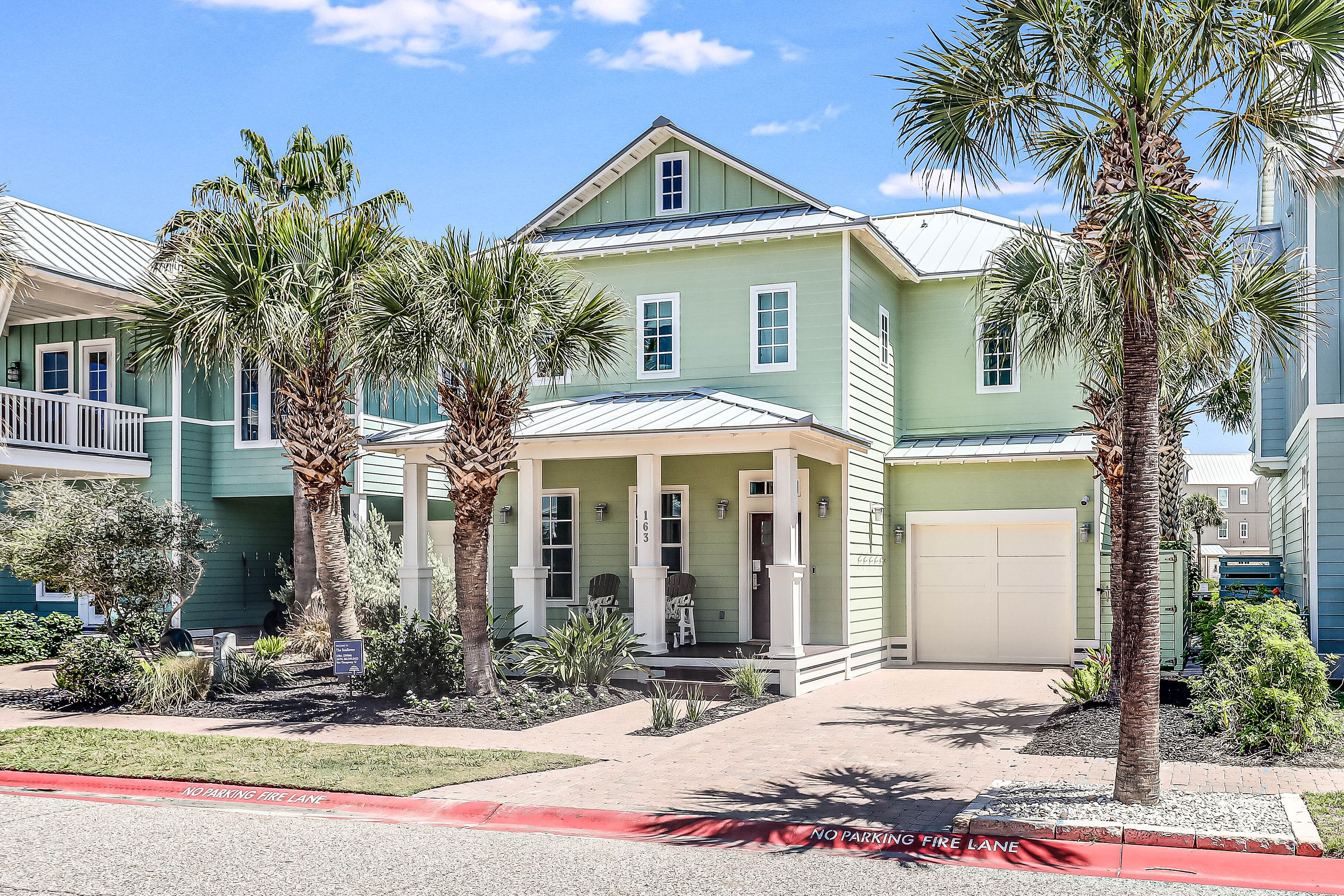 A two-story house with a green exterior, a covered porch, and a garage.