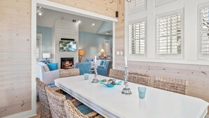 A dining area with a white table, wicker chairs, and a chandelier. - Shore House 183 BE (Port Aransas)