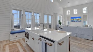 A spacious kitchen with a large island, white cabinetry, and a view of the ocean.
