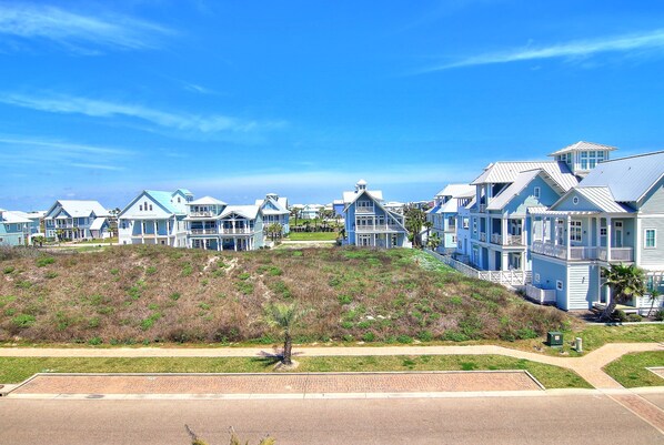 A coastal residential area with houses featuring balconies and a clear sky.