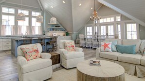 A spacious loft with a high ceiling, a kitchen with a large island, and a dining area with white furniture. - The Salty Dog 314 GR (Port Aransas)
