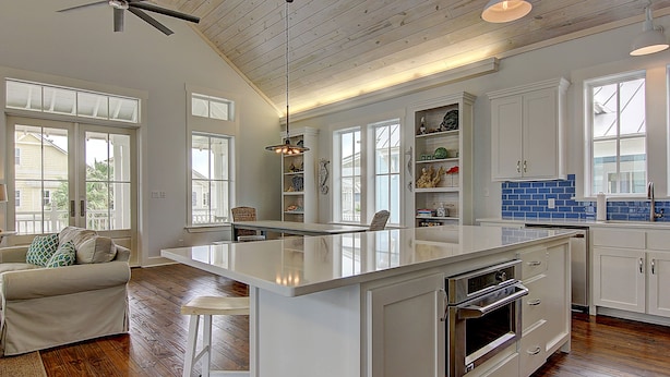 A spacious kitchen with a large island, white cabinetry, and wooden flooring. - Suits Us 231 BE (Port Aransas)