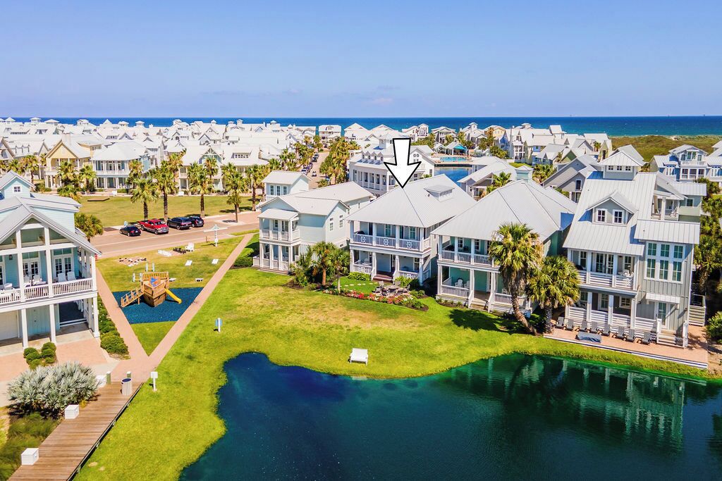 A coastal resort with multiple-story buildings, a central swimming pool, and a view of the ocean.
