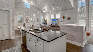 A spacious kitchen with a large island, white cabinetry, and a ceiling fan. - Sea Ya' Soon 130 ST (Port Aransas)