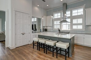 A modern kitchen with a central island, bar stools, pendant lighting, and large windows. - Sunset Regatta 230 GR (Port Aransas)