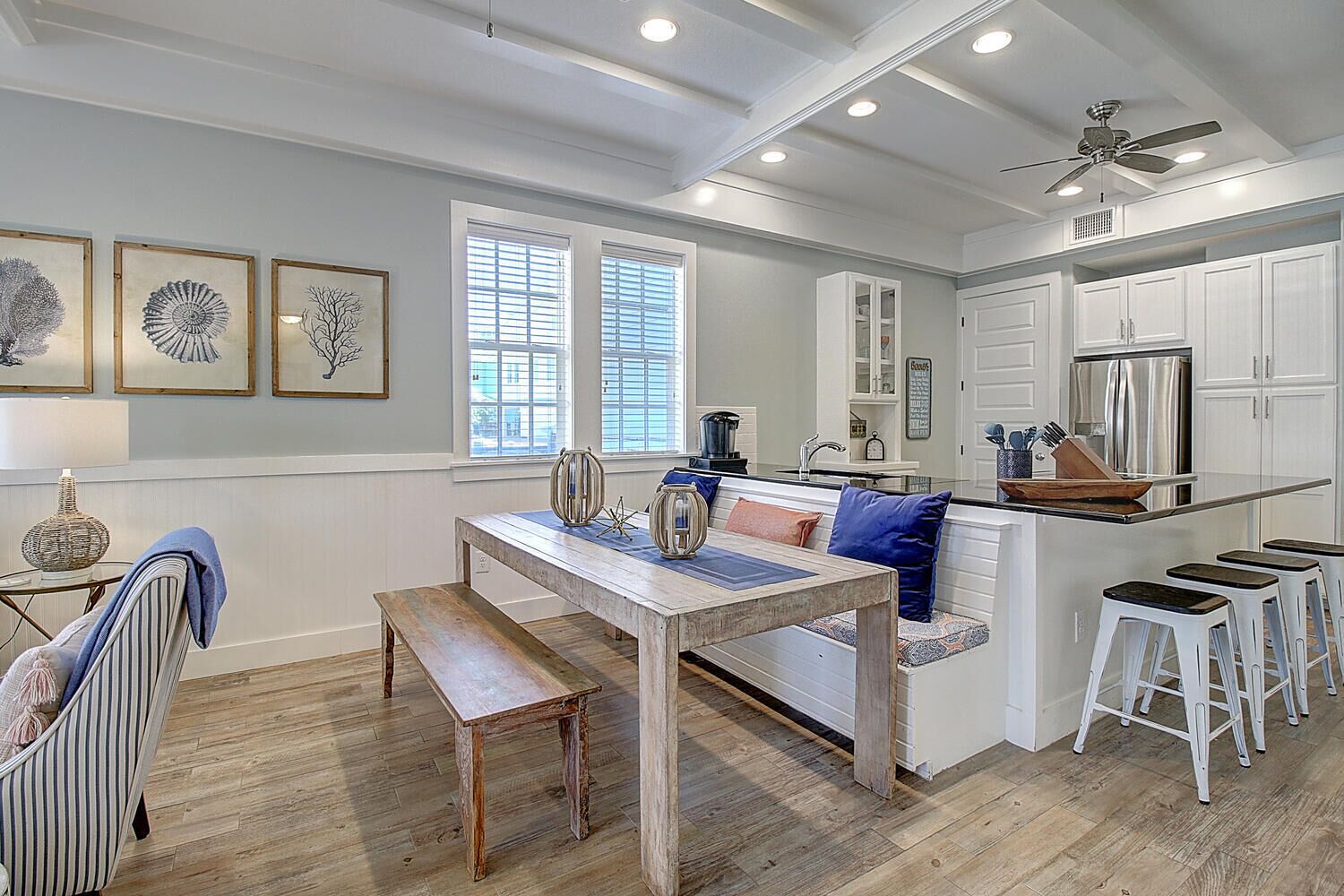 A modern kitchen with white cabinetry, a wooden dining table, and bar stools.