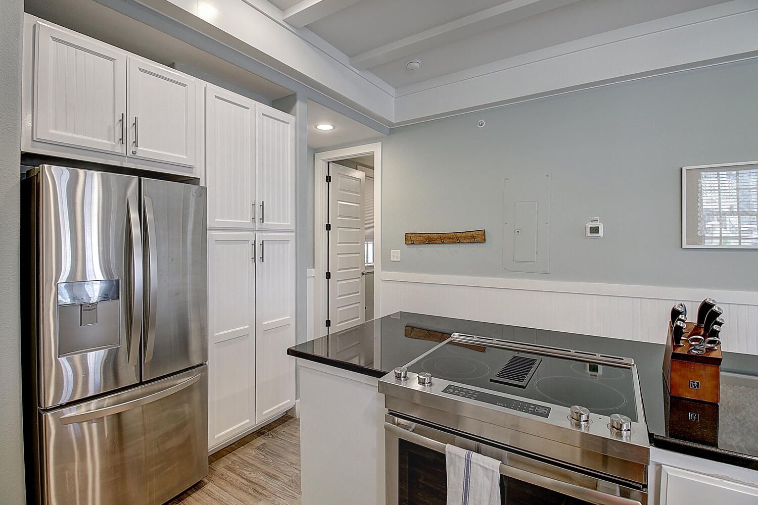 A modern kitchen with stainless steel appliances, white cabinetry, and a central island.