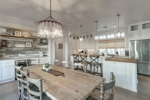 Enjoy cooking in this spacious kitchen with a large island, bar stools, and elegant chandelier.