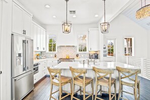 Enjoy cooking in this well-equipped kitchen with a central island, stainless steel appliances, and a herringbone-patterned backsplash.