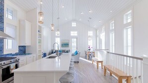 Una cocina amplia con una isla grande, armarios blancos y un salpicadero con azulejos azules.
