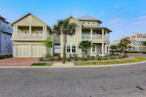 A two-story residential building with a balcony, a garage, and a well-maintained lawn.