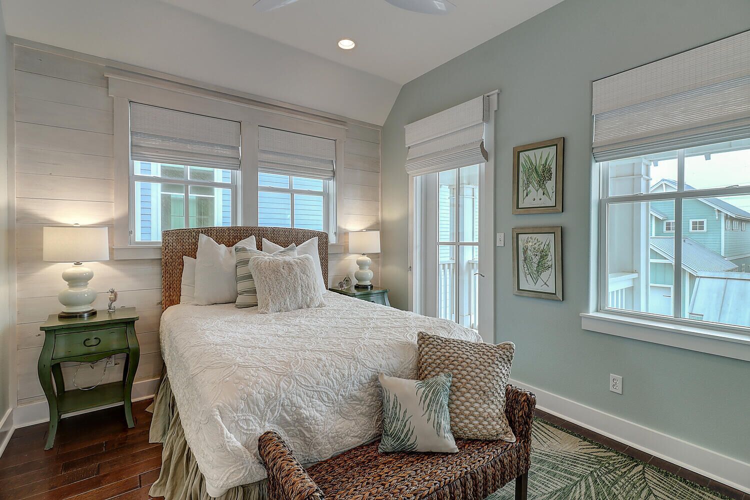 A bedroom with a large bed, two bedside tables, a chair, and a view of the outside through the window.