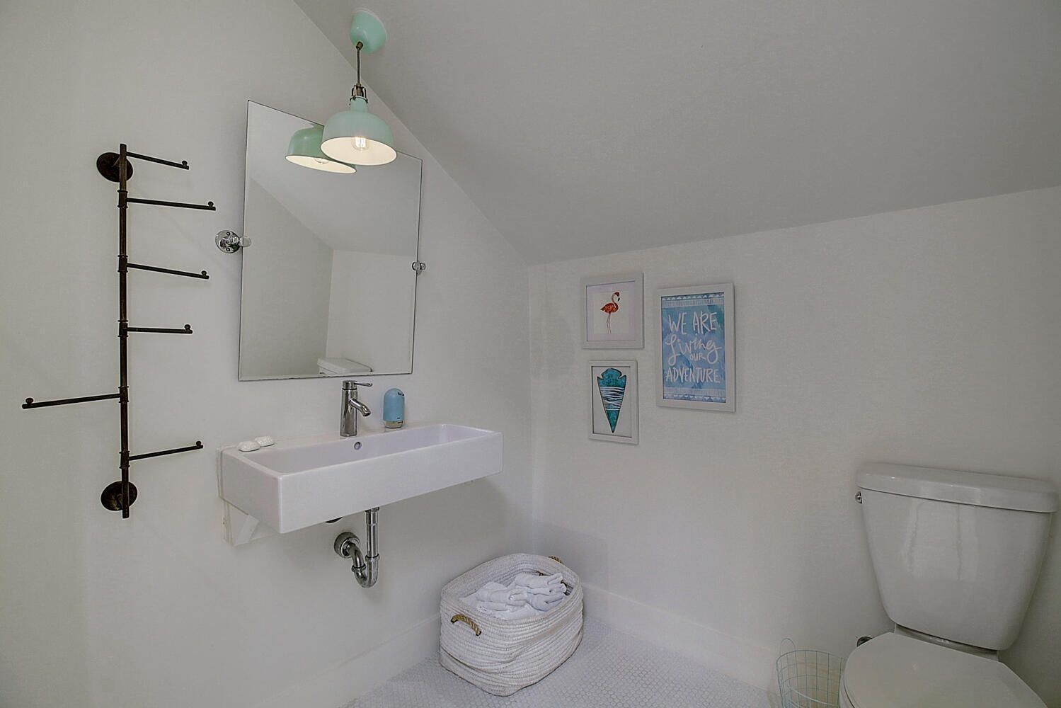 A bathroom with a white sink, a mirror, a toilet, and a towel rack.
