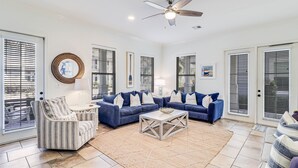 A spacious living room with a sectional sofa, a striped armchair, and a coffee table. - Shore Magic 116 ST (Port Aransas)