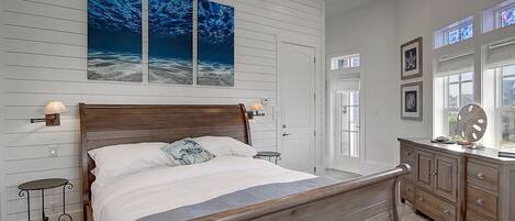 A bedroom with a wooden bed, a nightstand, a dresser, and a large window.
