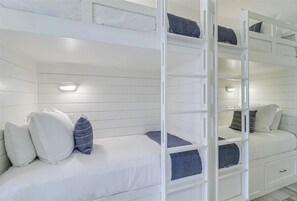 A bunk bed room with white walls and a white ceiling. There are two beds, one on the left and one on the right.