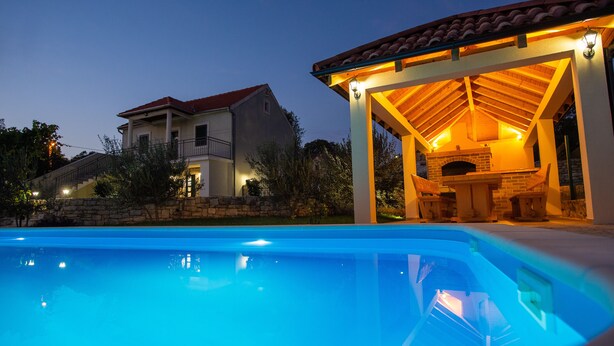 Une piscine avec un patio couvert et une cheminée en briques.