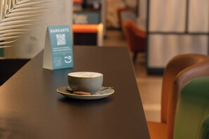 A coffee cup on a table with a QR code sign in the background. - Hey Lou Hotel Karlsruhe Messe (Rheinstetten)