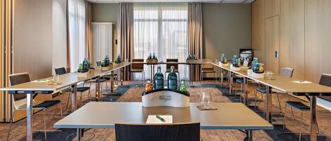 A conference room with long tables, chairs, and a projector screen.
