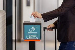 A person using an express checkout machine with a keycard. - Hey Lou Hotel Karlsruhe Messe (Rheinstetten)